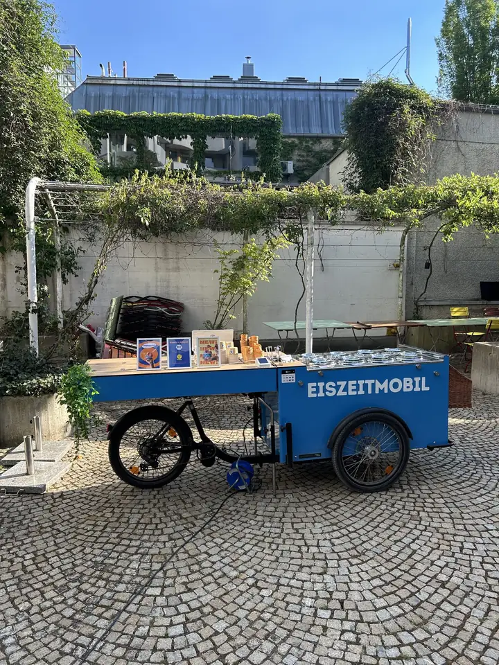 Das vollständige blaue Eiszeitmobil-Eisfahrrad in einem sonnigen, begrünten Innenhof